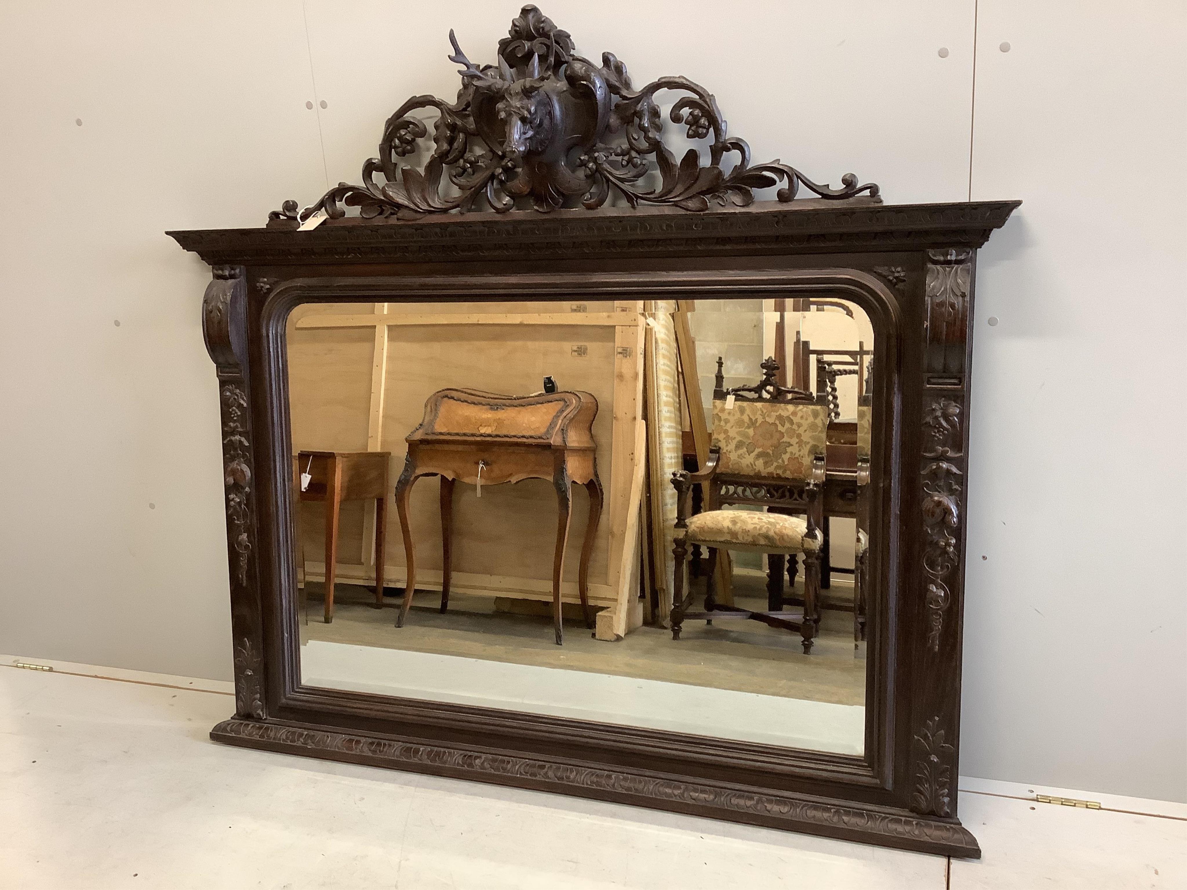 A Victorian oak overmantel mirror with carved stag's head pediment, width 163cm, height 146cm. Condition - fair